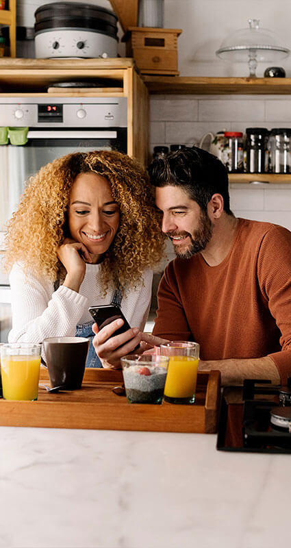 Eine Frau und ein Mann suchen auf dem Smartphone nach einem geeigneten Darlehen.
